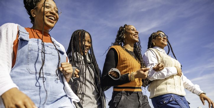 Group of four young African American teens and young adults, sisters or friends, happy outdoor portrait of togetherness, youth and female friendship