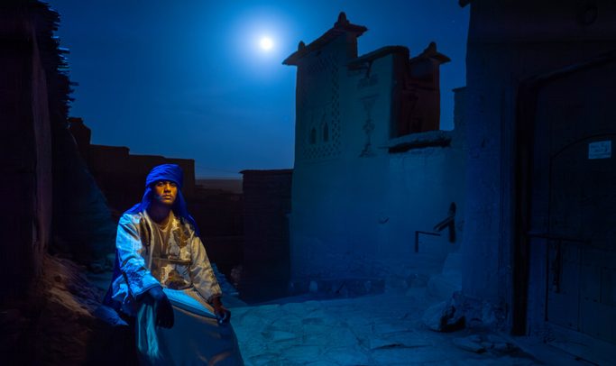 Berber Man in Blue Turban Under Full Moon at Ancient Moroccan KasbahShort description: