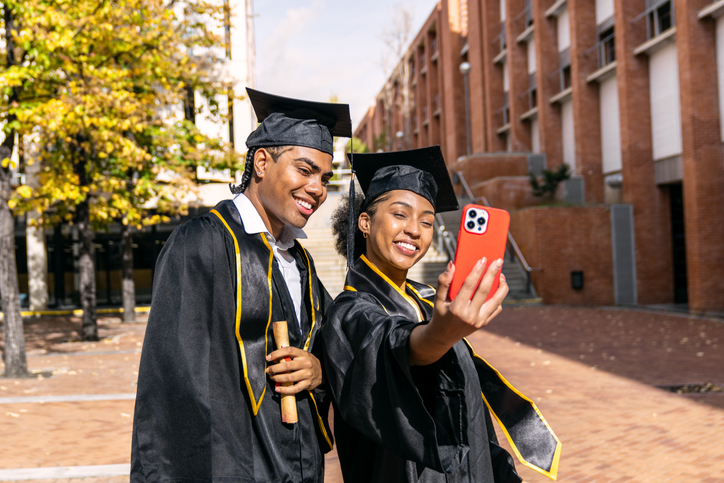 Young adult students celebrating graduation taking selfie