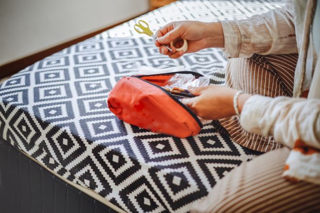 Plus-size middle-aged woman in the bedroom on the bed with a red bag a travel anxiety grab-and-go bag.