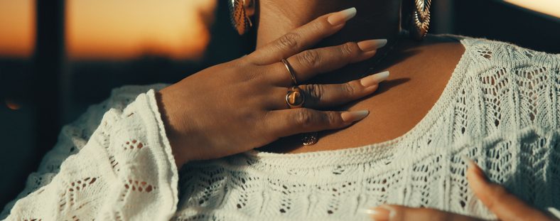 Close Up Of Woman Wearing White Crochet Top And Gold Jewelry At Sunset Outdoors
