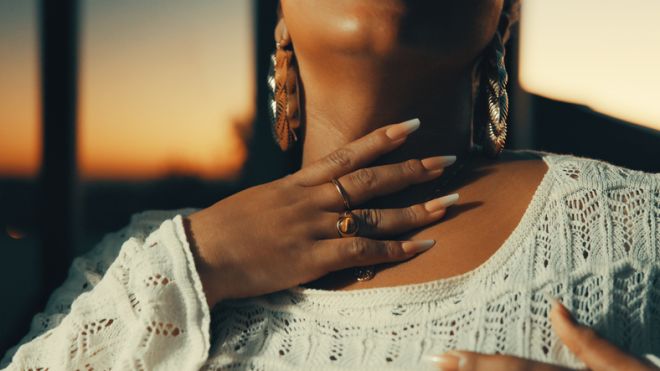 Close Up Of Woman Wearing White Crochet Top And Gold Jewelry At Sunset Outdoors
