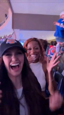 Two women laughing and making excited gestures in a crowded room.