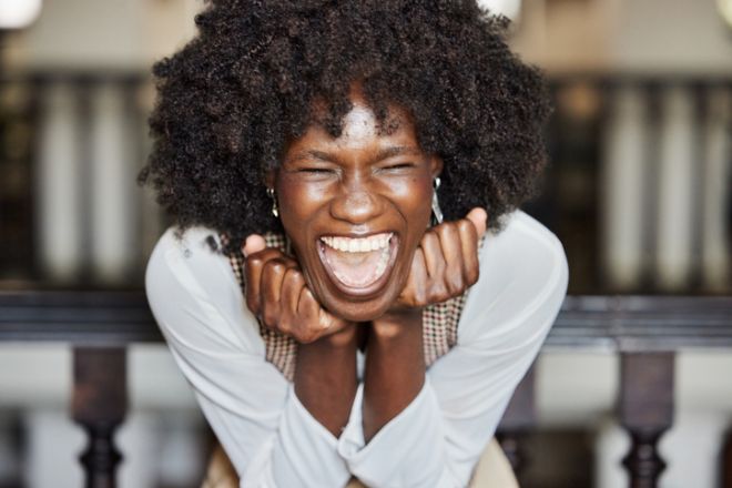 Happy black businesswoman screaming of joy in the office.