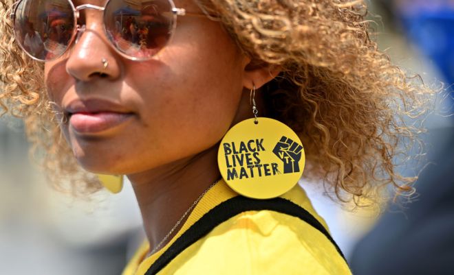 A black woman wears handmade Black Lives Matter earing to a