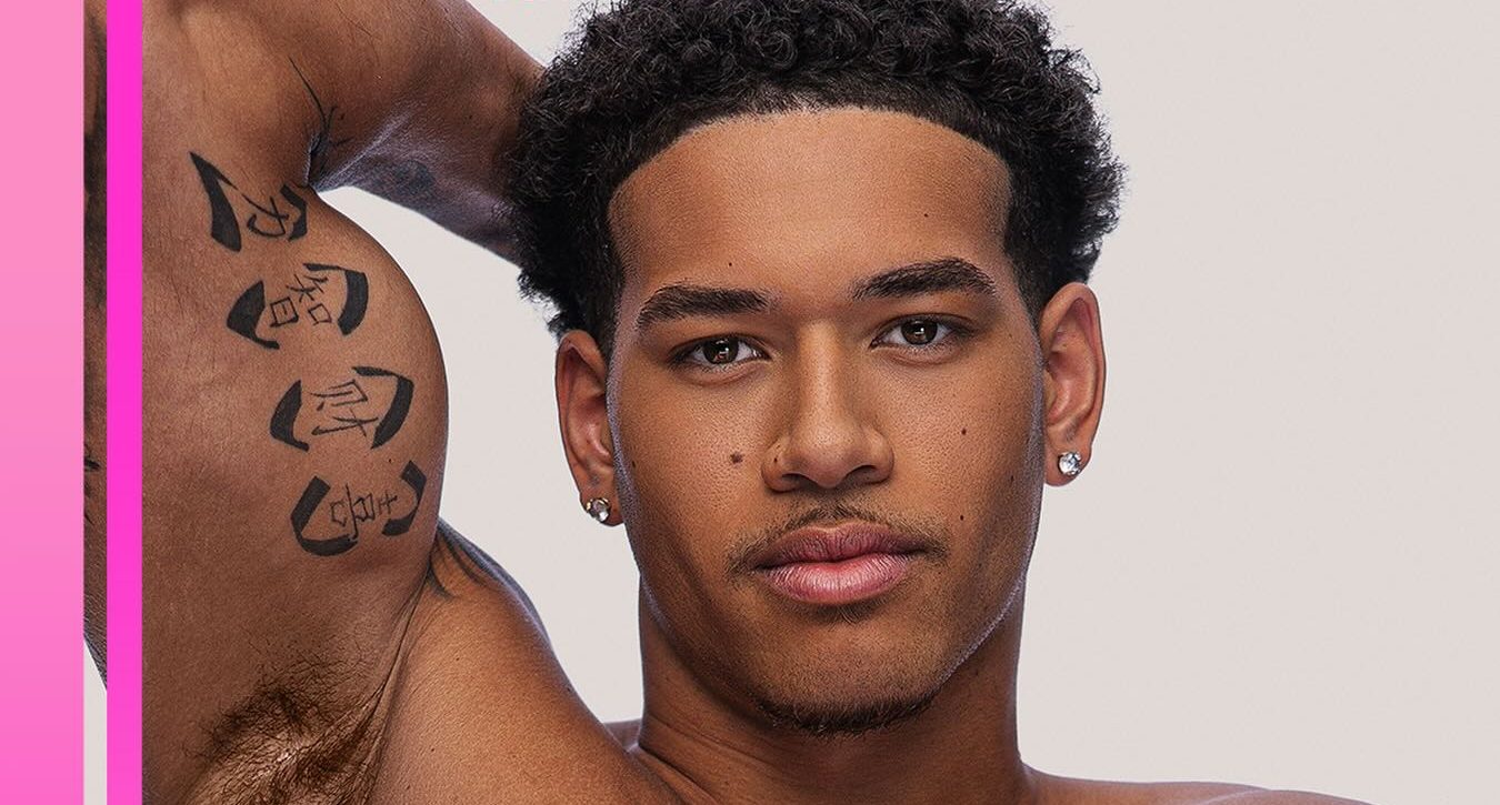 Shirtless man with curly hair and tattoos posing against a pink and white background with "Love Island USA" and "Peacock" branding.