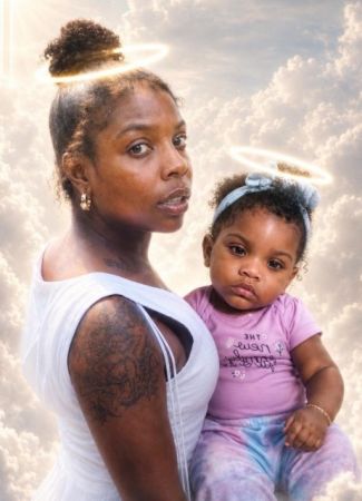 A woman holding a young child in her arms, both looking directly at the camera, against a cloudy sky background.