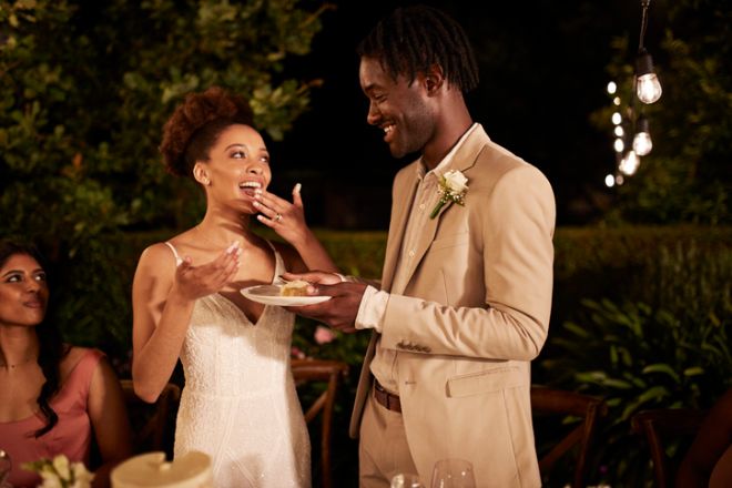 Happy newlywed couple enjoying cake at dinner party
