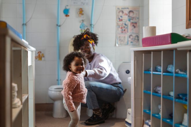Toddler smiling during potty training at daycare bathroom
