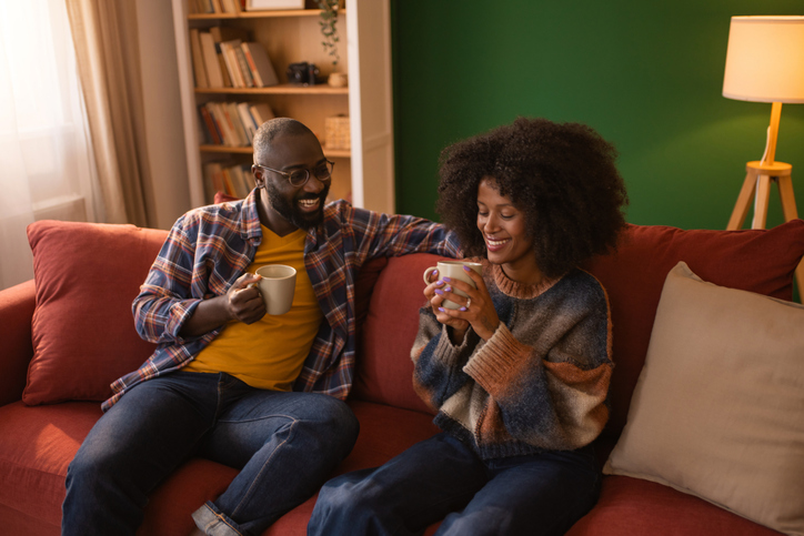 African couple relaxing on sofa enjoying morning coffee