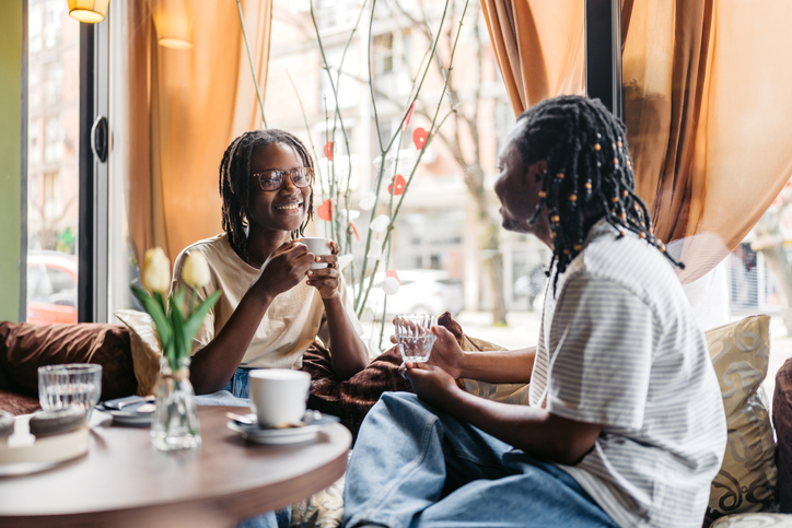 Young Black Male And Female Friend Drinking Coffee And Talking In A Sidewalk Café