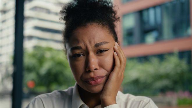 Face African American woman touch jaw toothache ill health dentistry patient female girl discomfort suffer sick caries dental ache teeth oral disease unwell unhappy businesswoman business city outside
