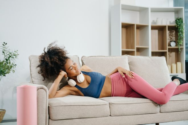 Active woman in athleisure sitting on yoga mat with tablet, headphones and modern home lifestyle.