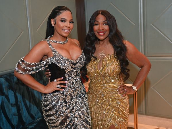 Two women in glamorous dresses posing together, one in a sparkling black dress and the other in a gold sequined gown.