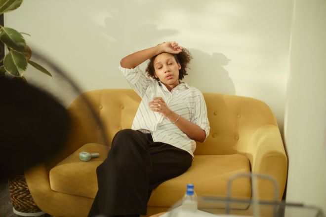 Black Adult Woman Resting on Sofa during Heatwave at Home