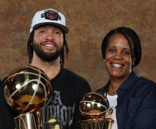 Four people, three men and one woman, posing together and holding up NBA championship trophies.
