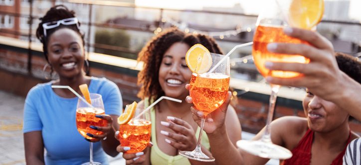 Company of four cheerful friends are enjoying tasty cocktails. Roof party