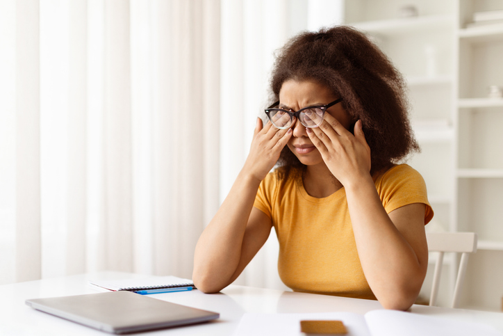 Exhausted black woman rubbing tired eyes, suffering from eyestrain after using laptop