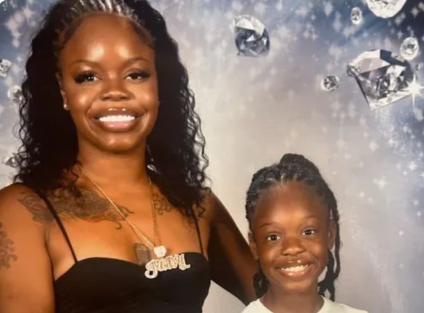 Two smiling Black women, one adult and one child, posing in front of a sparkling background.