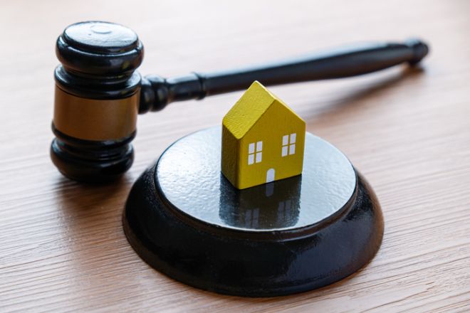 A small yellow house model and a judge's gavel.