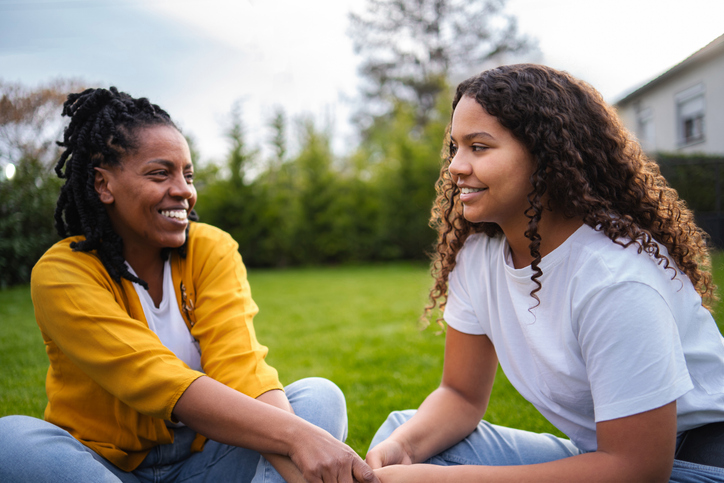 Mother and daughter talking, sharing bonding moment outdoors