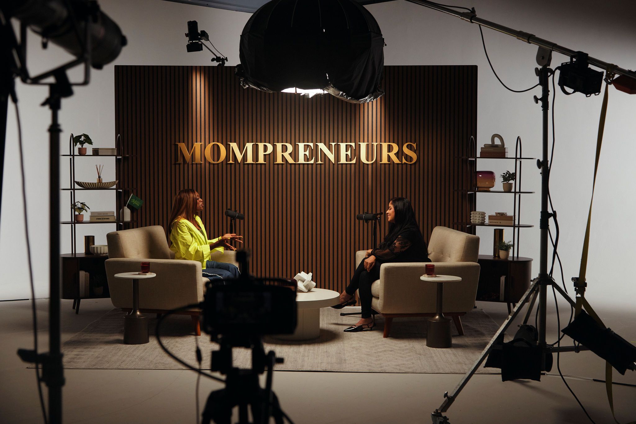 Two women sitting in chairs in a studio setting, with