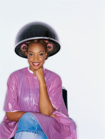 Portrait of a young woman under a hair dryer