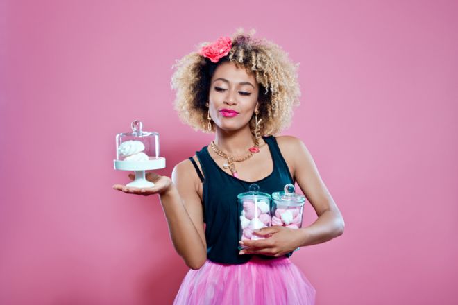 Studio portrait of afro woman holding cookies