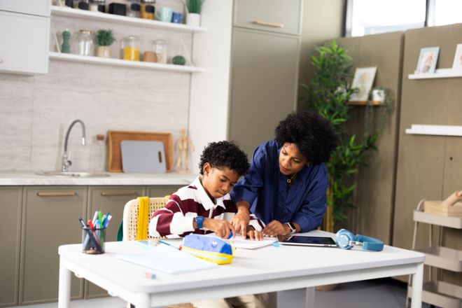 Mother helping son with homework at home kitchen
