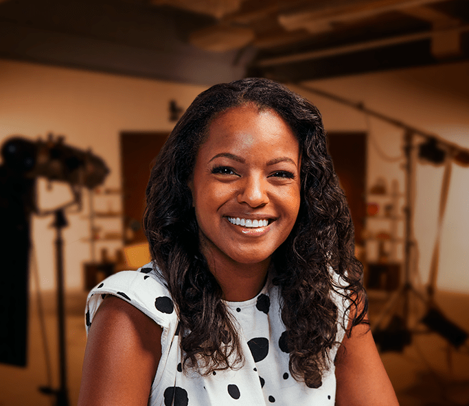 A smiling woman with curly dark hair wearing a polka dot blouse.
