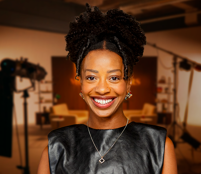A smiling woman with curly black hair wearing a black top and silver necklace.