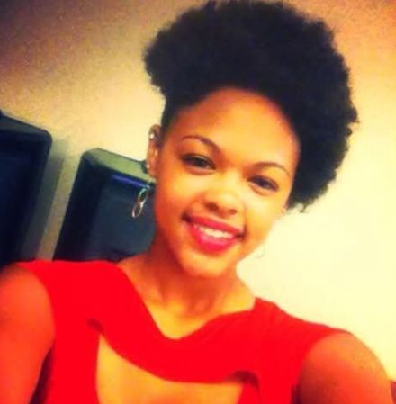 A smiling woman with an afro hairstyle wearing a red top.