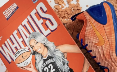 A woman wearing a black basketball jersey with the number 22 and the text "Ipsy" on it, holding a basketball. Next to the jersey is a pair of orange and blue basketball shoes.
