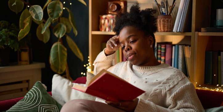 Black Woman Reading Book on Sofa in Cozy Living Room