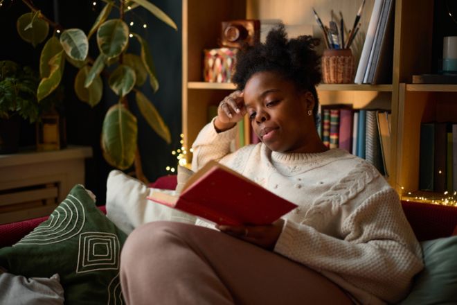 Black Woman Reading Book on Sofa in Cozy Living Room
