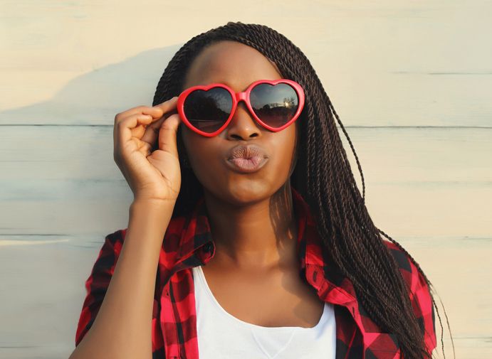 Happy young African woman in red heart shaped glasses, beautiful black girl in sunglasses