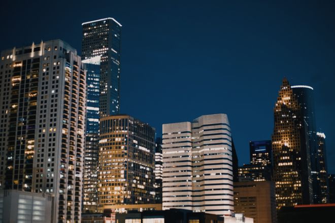 Low angle view of illuminated modern city buildings against a dark blue night sky, showcasing urban architecture and city life after dark,Houston,United States,USA,Downtown Houston