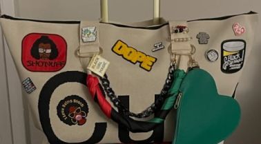 A backpack with various patches, pins, and stickers, including a "Schoolhouse" logo, a heart-shaped "Love" patch, and a "Dunk" logo.