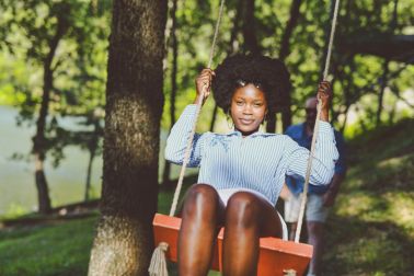 Joyful Woman Smiling as Her Husband is Gently Pushing Her on Swing
